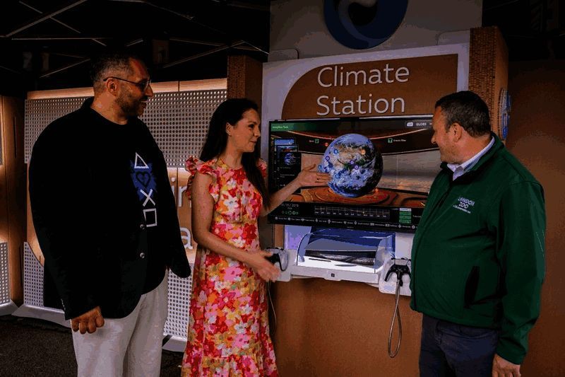 学生使用《气象档案馆》进行课堂学习,教师在一旁指导操作,屏幕显示全球气温变化动画