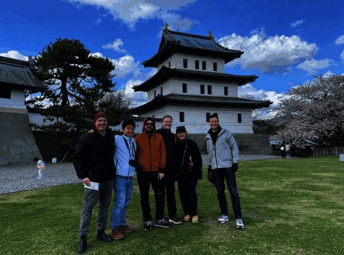 开发团队成员在羊蹄山脚下开心交谈，周围绿意盎然