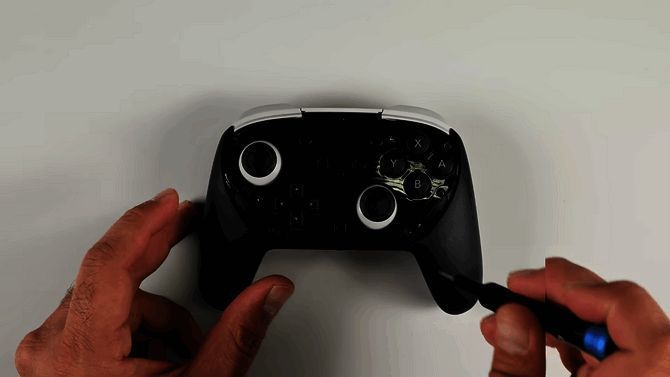 iFixit主播正在对NS2 Pro手柄进行初步拆解,桌上摆放着各类精密工具