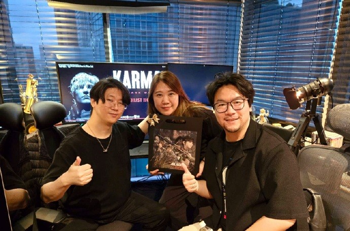 金亨泰与王勇赫在韩国会面合影,两人手持《黑暗世界:因与果》主题立牌,背景为充满冷峻工业风的展台